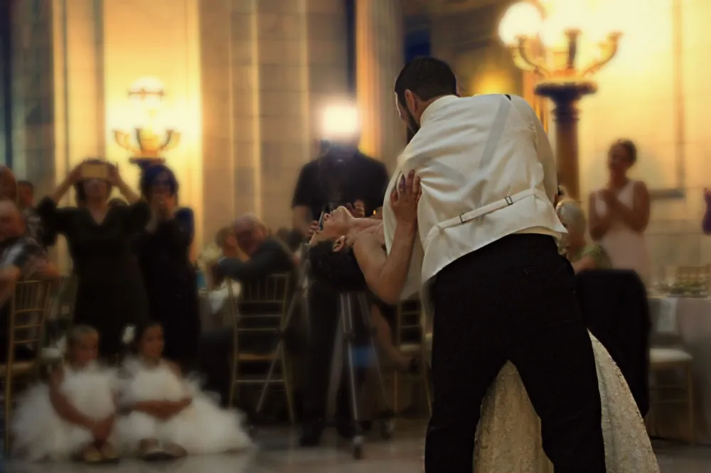 Newlyweds sharing a first dance at their wedding reception while guests look on